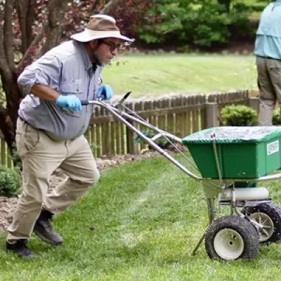 TLC lawn technician fertilizing yard